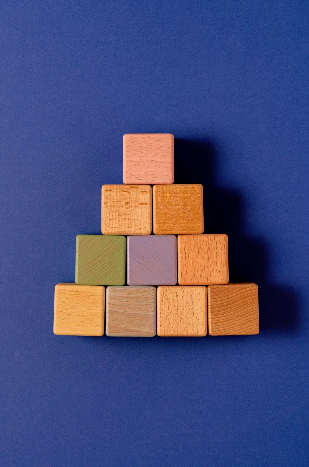 A pyramid structure made of various colored wooden blocks on a blue background, symbolizing the foundational layers and structured growth in SEO and link building strategy.
