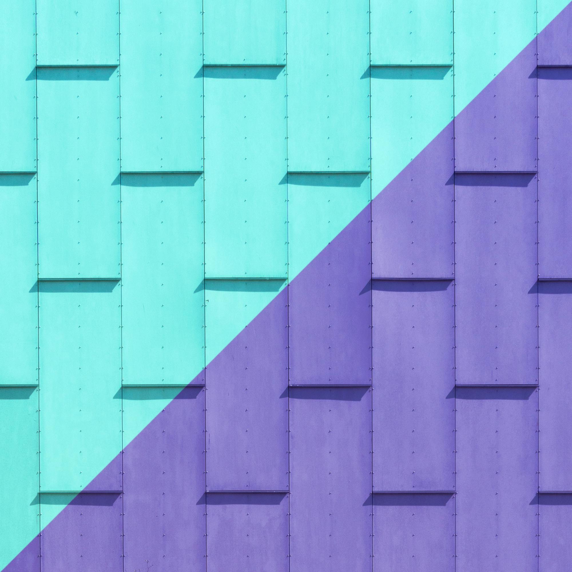 A vibrant and modern wall with a diagonal split in color, featuring turquoise and purple geometric panels, symbolizing contemporary design and strategic visual balance.